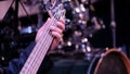 The musician`s hand clamps the strings on a five-string electric bass. Performance by an orchestra or a jazz band. Guitar player