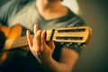 A musician in a t-shirt plays a tune on an old acoustic guitar Royalty Free Stock Photo