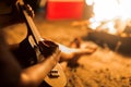 A musician woman playing ukulele guitar next to a campfire on the beach