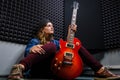 Musician woman sitting with a red electric guitar in his hands. A young woman guitarist in jeans with a beautiful guitar.