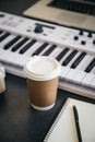 Musician workplace table with paper cup and white piano keyboard. Royalty Free Stock Photo