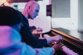 Musicians from diverse backgrounds work together on a music project, using a piano in a studio. Royalty Free Stock Photo