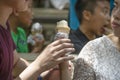 Young couple share ice cream cone with children eating ice cream blurred behind - Asian ethnicity