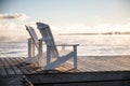 Muskoka Chairs on a dock with sun rising and mist Royalty Free Stock Photo