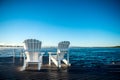 Muskoka Chairs on a dock with sun rising and mist Royalty Free Stock Photo