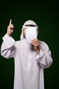 Muslim anonymous concept. Arab person holds digital tablet, face covered, index finger up, representing the concept of