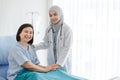 Muslim Arab Islam female doctor wears grey hijab and white lab coat uniform with stethoscope standing look at camera visiting