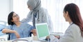 Muslim Arab Islam wears hijab and Asian female doctor in white lab coat uniform with stethoscope consulting asking discussing with