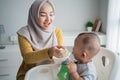 Mother feeding her baby boy while sitting on high chair Royalty Free Stock Photo