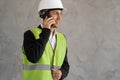 Muslim Builder with phone. Man in construction worker's uniform. Repairman in vest and helmet. Foreman on grey