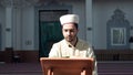 Muslim cleric reading quran with mask