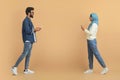 Muslim couple engrossed in their mobile phones while walking past each other