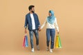 Muslim couple enjoying shopping together, holding hands and carrying colorful bags Royalty Free Stock Photo