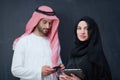 Muslim couple using modern technology in front of black chalkboard