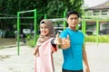 Muslim couples stand back to back exercising in the park showing thumb up