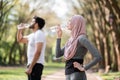 Muslim family in activewear drinking water at park