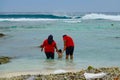 Muslim family slowly enters the ocean as a big barrel wave approaches the shore.