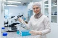 Muslim female chemistry student in hijab sitting at a table in a research laboratory and studying liquid substances Royalty Free Stock Photo