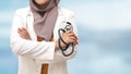 Muslim female doctor wearing hijab and suit, standing with crossed arm and holding stethoscope, succesful confident person Royalty Free Stock Photo