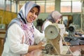 Muslim female employees wearing headscarves smile while working using sewing machines