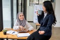 A Muslim female office worker enjoys chatting with her colleague during a coffee break Royalty Free Stock Photo