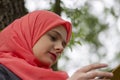 Muslim female student reading a book in nature, outdoor