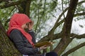 Muslim female student reading a book in nature, outdoor