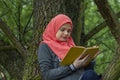 Muslim female student reading a book in nature, outdoor