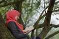 Muslim female student reading a book in nature, outdoor