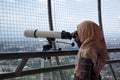 Muslim female tourists see the view of Purwokerto City using telescope at the Lotus View Tower Royalty Free Stock Photo