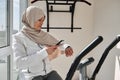 Muslim fit woman checking her fitness track and her heart rate after cardio workout on stationary bike Royalty Free Stock Photo