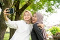 muslim friend taking selfie or video calling outdoor using her smart phone during sport break outdoor Royalty Free Stock Photo