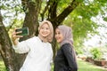 muslim friend taking selfie or video calling outdoor using her smart phone during sport break outdoor Royalty Free Stock Photo