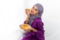 Muslim girl celebrates end of Ramadan, dressed in traditional purple dress, and holding a must-have traditional food Royalty Free Stock Photo