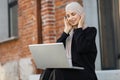 Muslim girl in hijab wearing wireless headphones, listening favorite songs online working on laptop Royalty Free Stock Photo