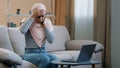 Muslim islamic arabian woman in pink hijab sitting on sofa working using laptop feel headache stress migraine severe