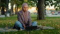 Muslim islamic student girl in hijab business woman freelancer user uses laptop sitting on green grass in park working Royalty Free Stock Photo