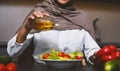 Muslim Lady Cooking Drizzling Olive Oil On Salad In Kitchen