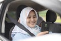 Muslim Lady Smiling When Looking at Her Phone in The Car Royalty Free Stock Photo