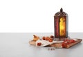 Muslim lamp, dates and prayer beads on table against white background