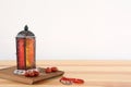 Muslim lantern Fanous, dried dates and prayer beads on table against light background.