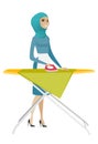 Muslim maid ironing clothes on ironing board.
