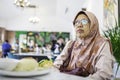 Muslim Malaysian elderly woman waiting patiently in front of her food in a local restaurant Royalty Free Stock Photo