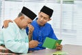 Muslim man comforting his father after reading a greeting card