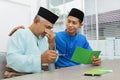 Muslim man comforting his father after reading a greeting card