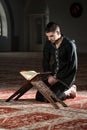 Muslim Man In Dishdasha Is Reading The Quran Royalty Free Stock Photo