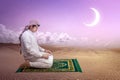 Muslim man with keffiyeh with agal in praying position salat on the prayer rug