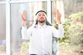 Muslim man with misbaha praying near windows