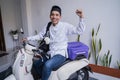Muslim man ride motorcycle for idul fitri balik kampung mudik carrying suitcase