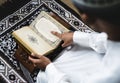 Muslim man sitting on a prayer rug reading Quran